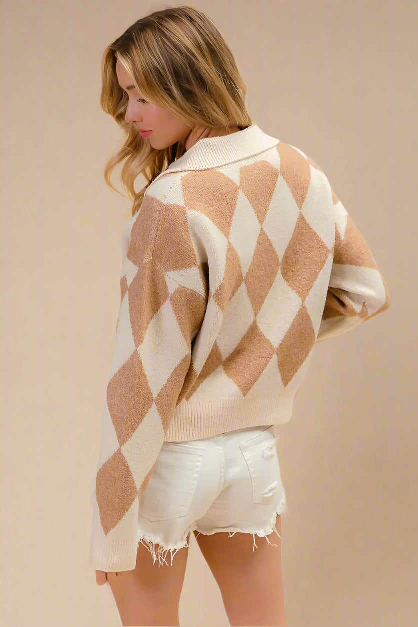 Woman wearing a beige and white diamond patterned sweater with white shorts on a beige background