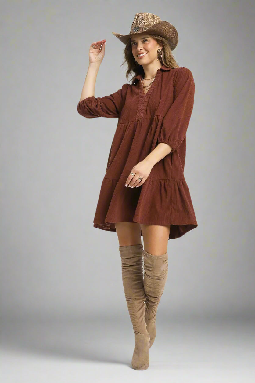 Woman wearing a red brown dress and tan boots on a white background