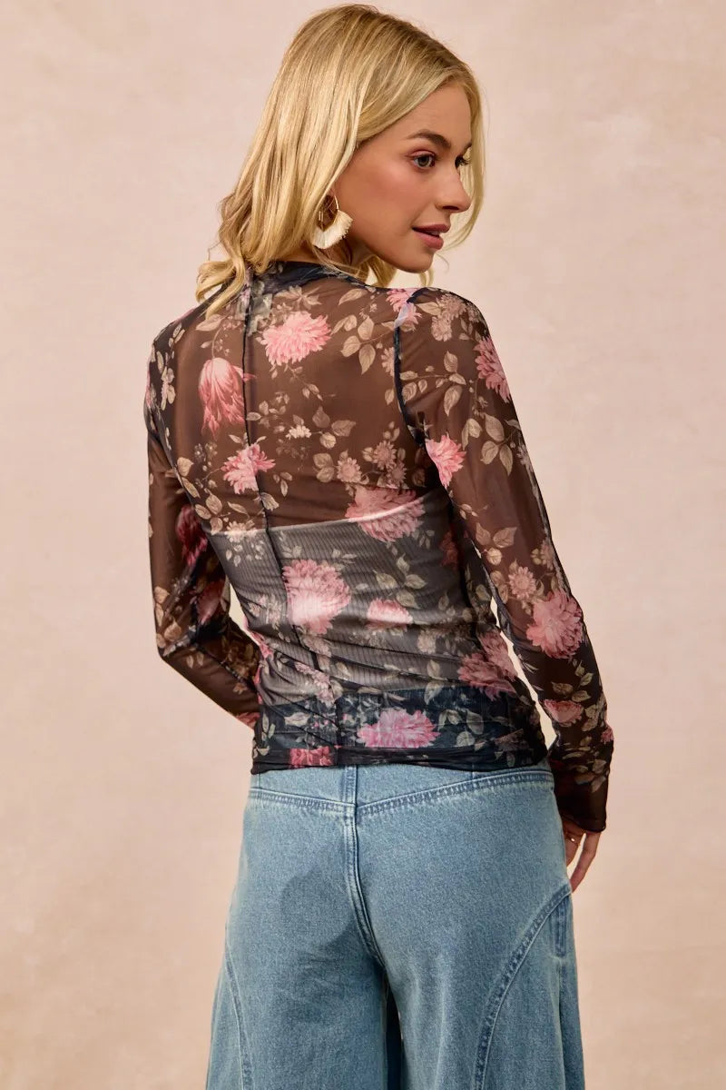 Woman wearing a floral blouse with long sleeves and jeans on a beige background