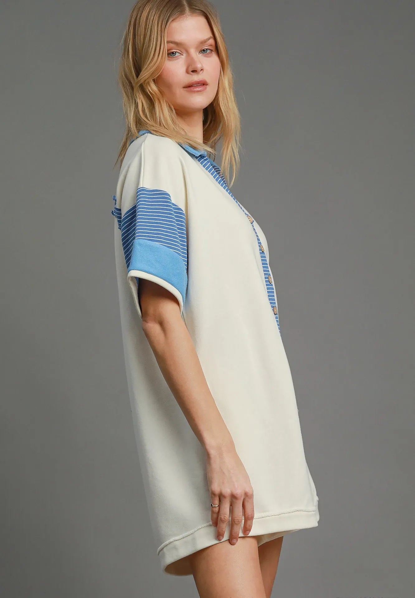 Woman wearing a white dress with blue stripes on a gray background