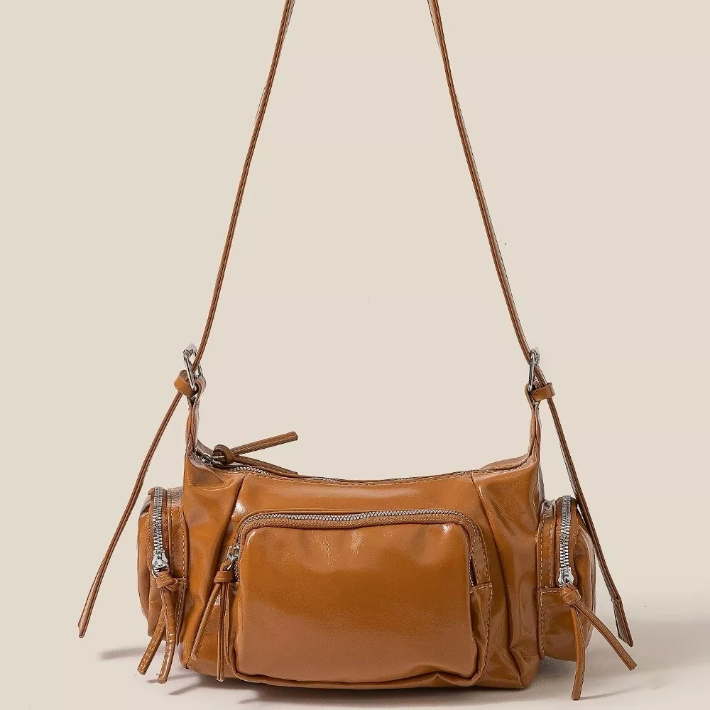 Brown leather handbag with multiple pockets and zippers on a beige background