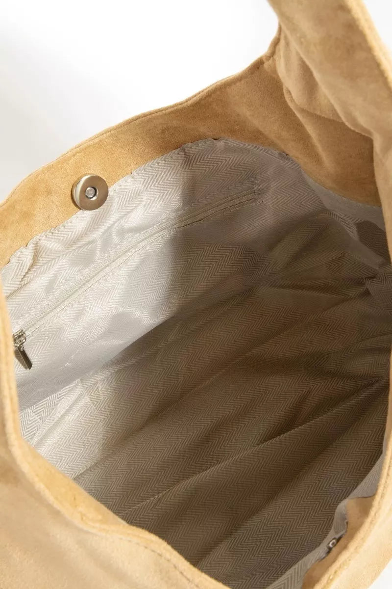 Close-up of a beige bag with a zipper and button detail on a white background