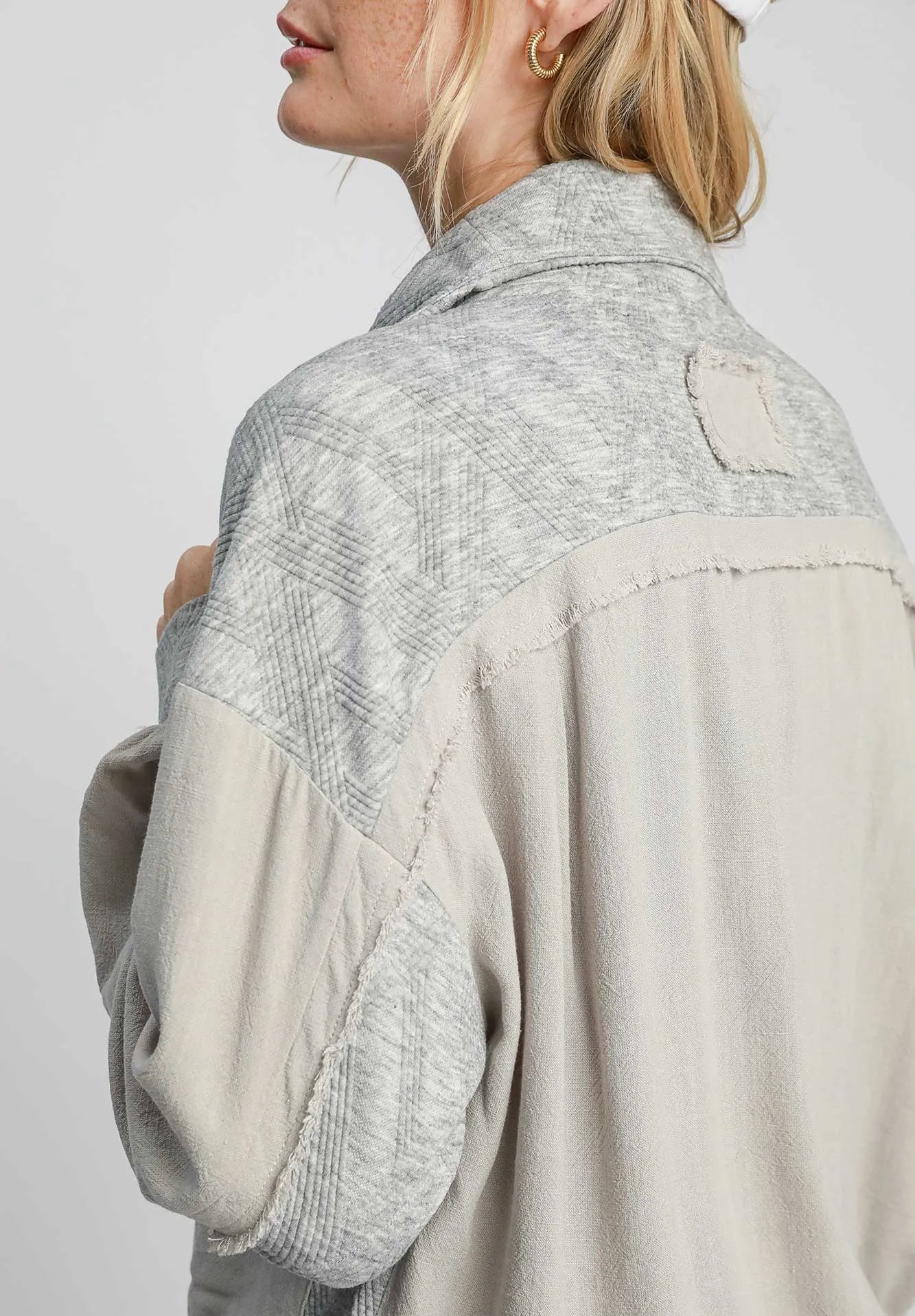 Person wearing a two-tone jacket with geometric patterns on a plain background