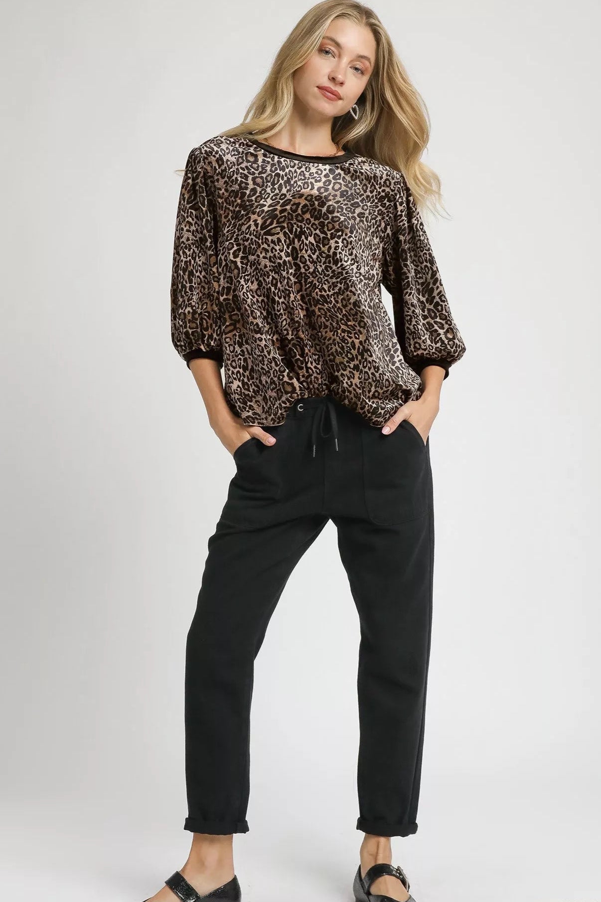 Woman wearing a brown sequin top and black pants on a white background