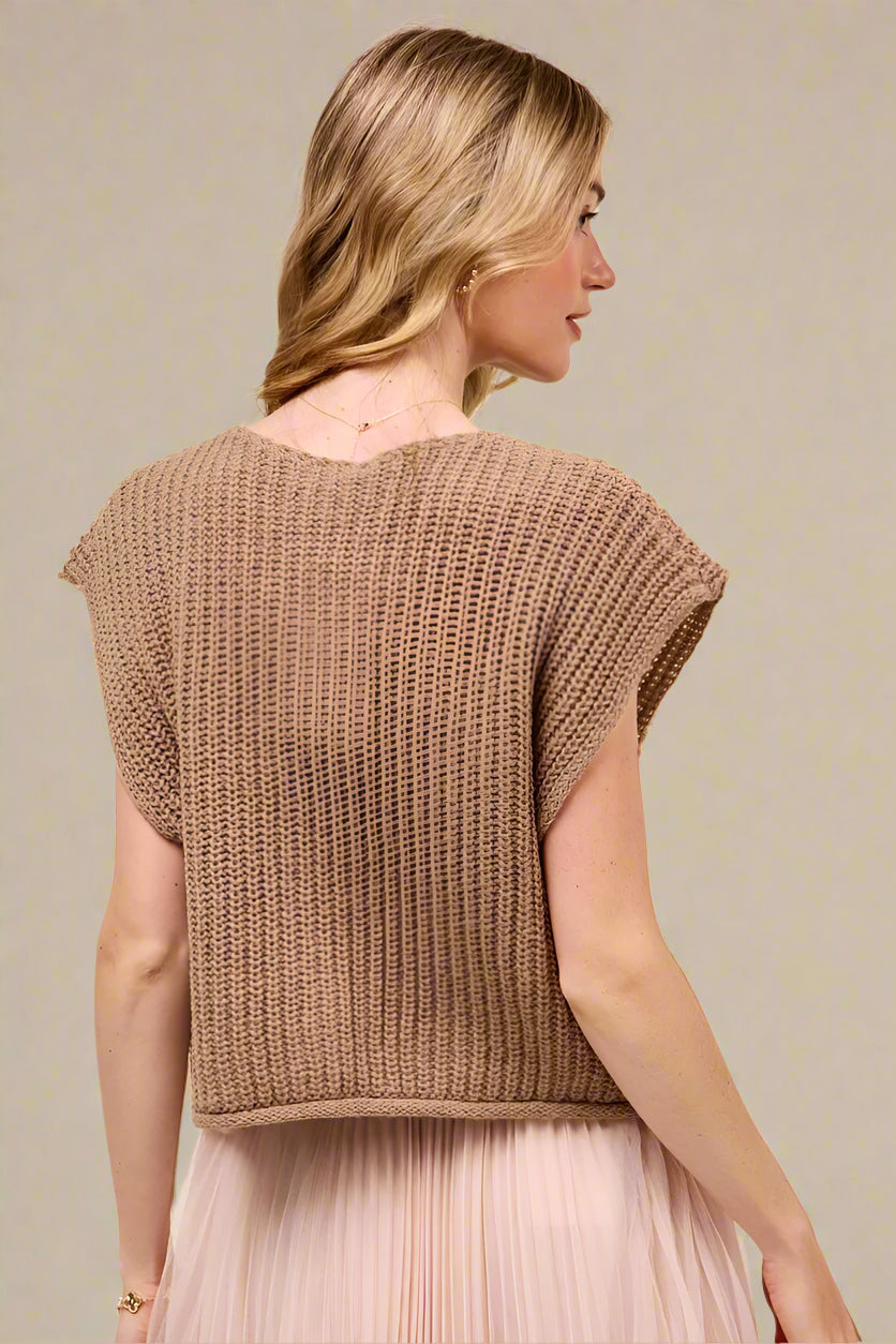 Woman wearing a brown knitted top against a beige background