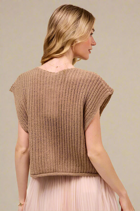 Woman wearing a brown knitted top against a beige background