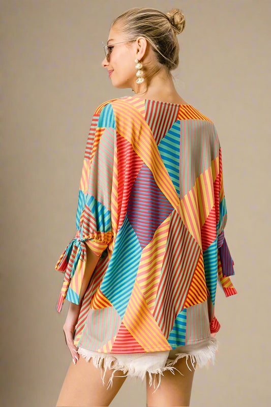 Woman wearing a colorful patterned top with a beige background