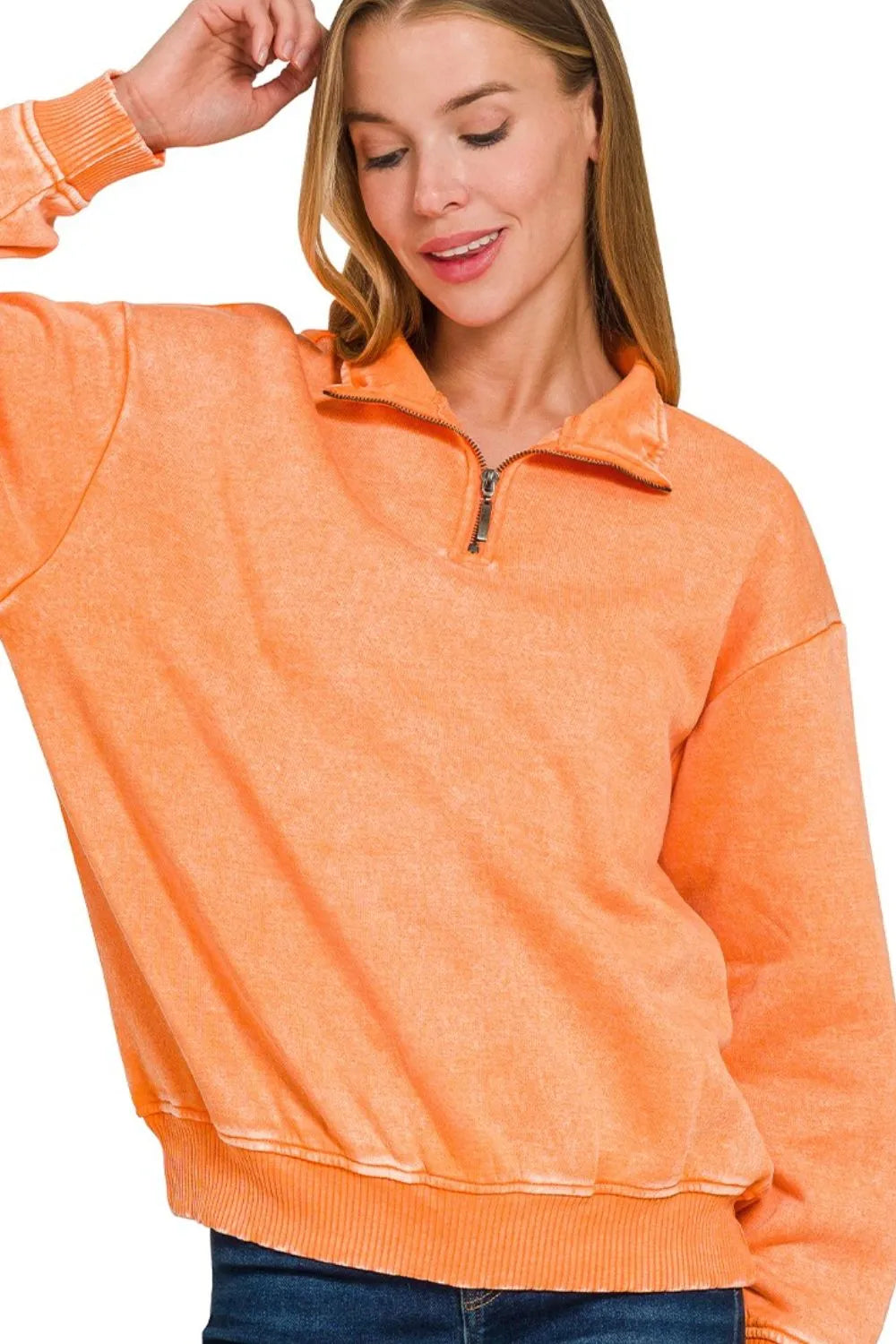 Woman wearing an orange pullover with a zipper on a white background