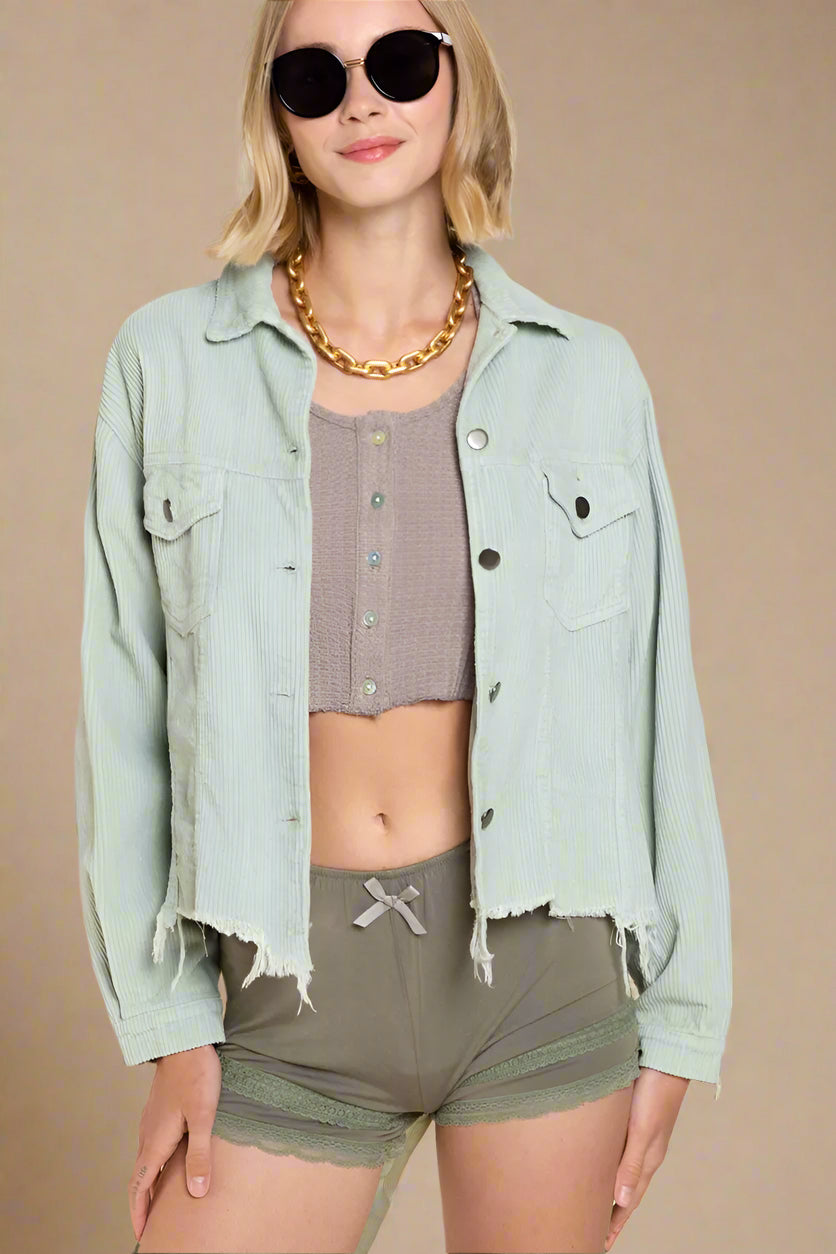 Woman wearing a light green denim jacket, checkered top, and green shorts on a beige background