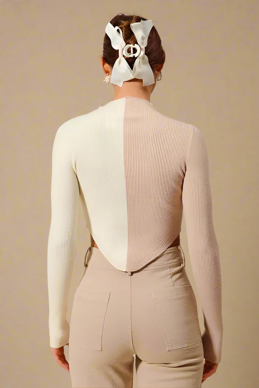 Person wearing a two-tone sweater with a geometric design on a beige background