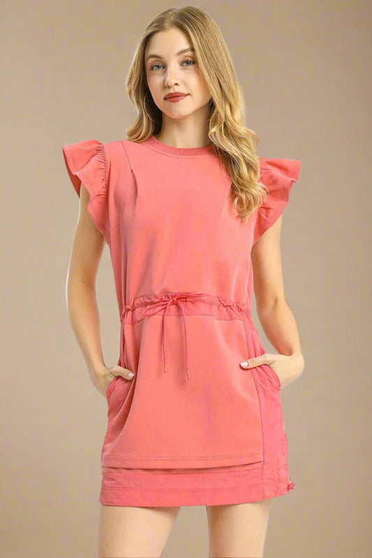 Woman wearing a coral dress with ruffled sleeves on a white background