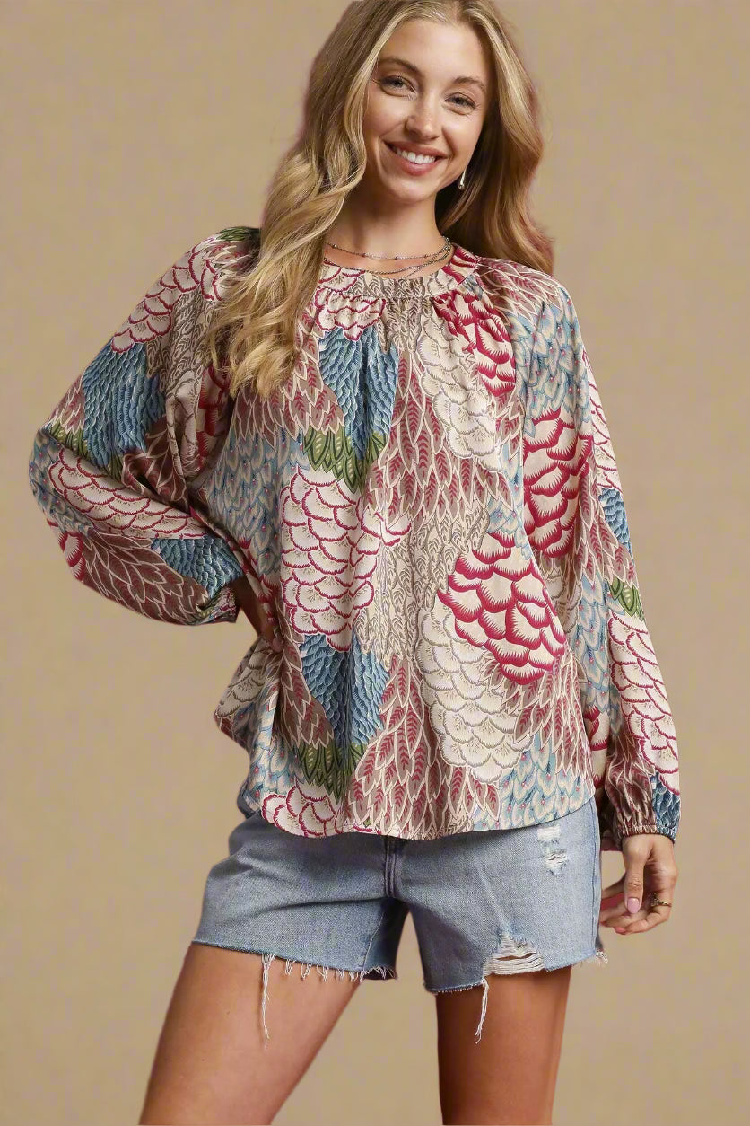 Woman wearing a patterned blouse and denim shorts on a red background