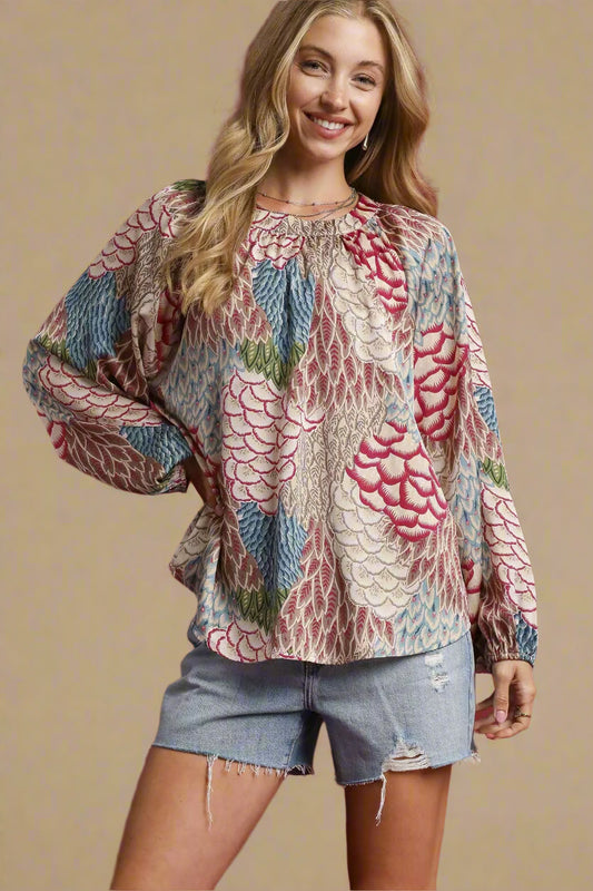 Woman wearing a patterned blouse and denim shorts on a red background