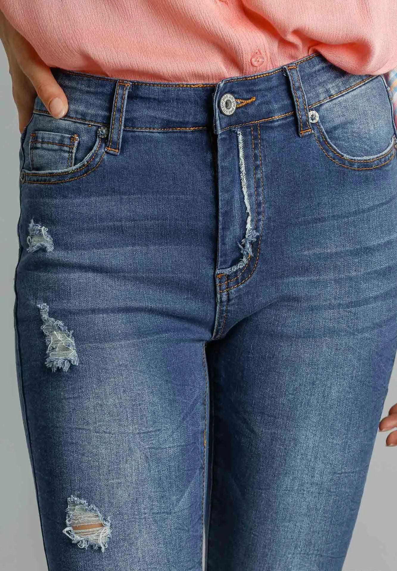 Close-up of blue jeans with distressed details on a gray background