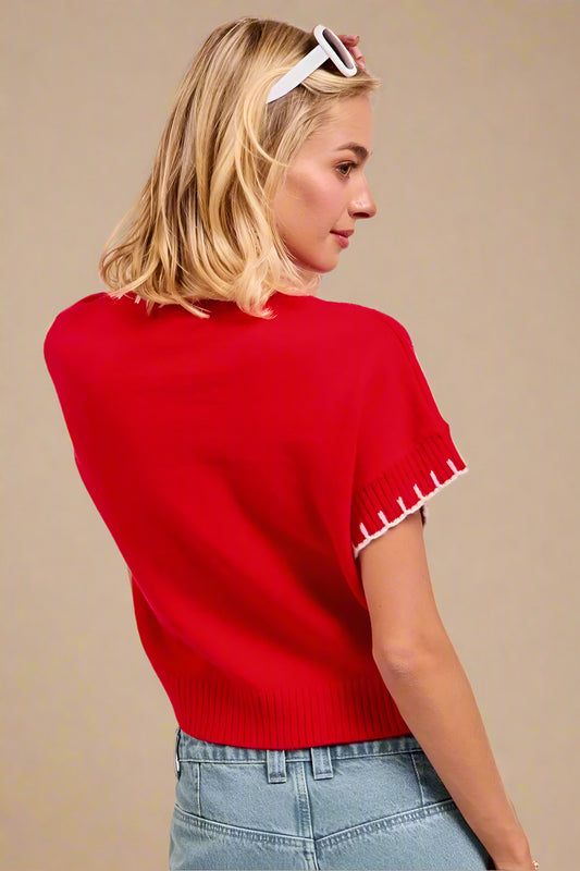 Woman wearing a red sweater with white trim on a beige background
