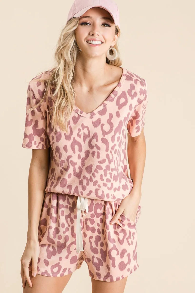 Woman wearing a pink leopard print outfit with a matching cap on a beige background