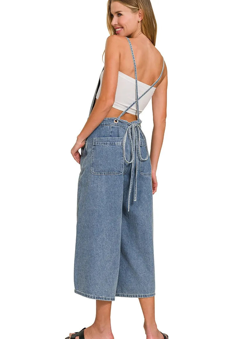 Woman wearing a white crop top and blue denim wide-leg pants on a white background