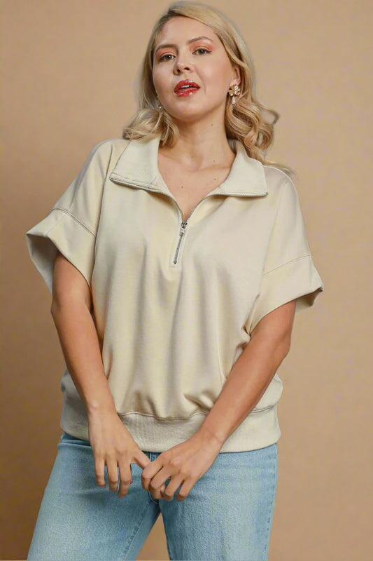 Woman wearing a beige top and blue jeans on a gray background