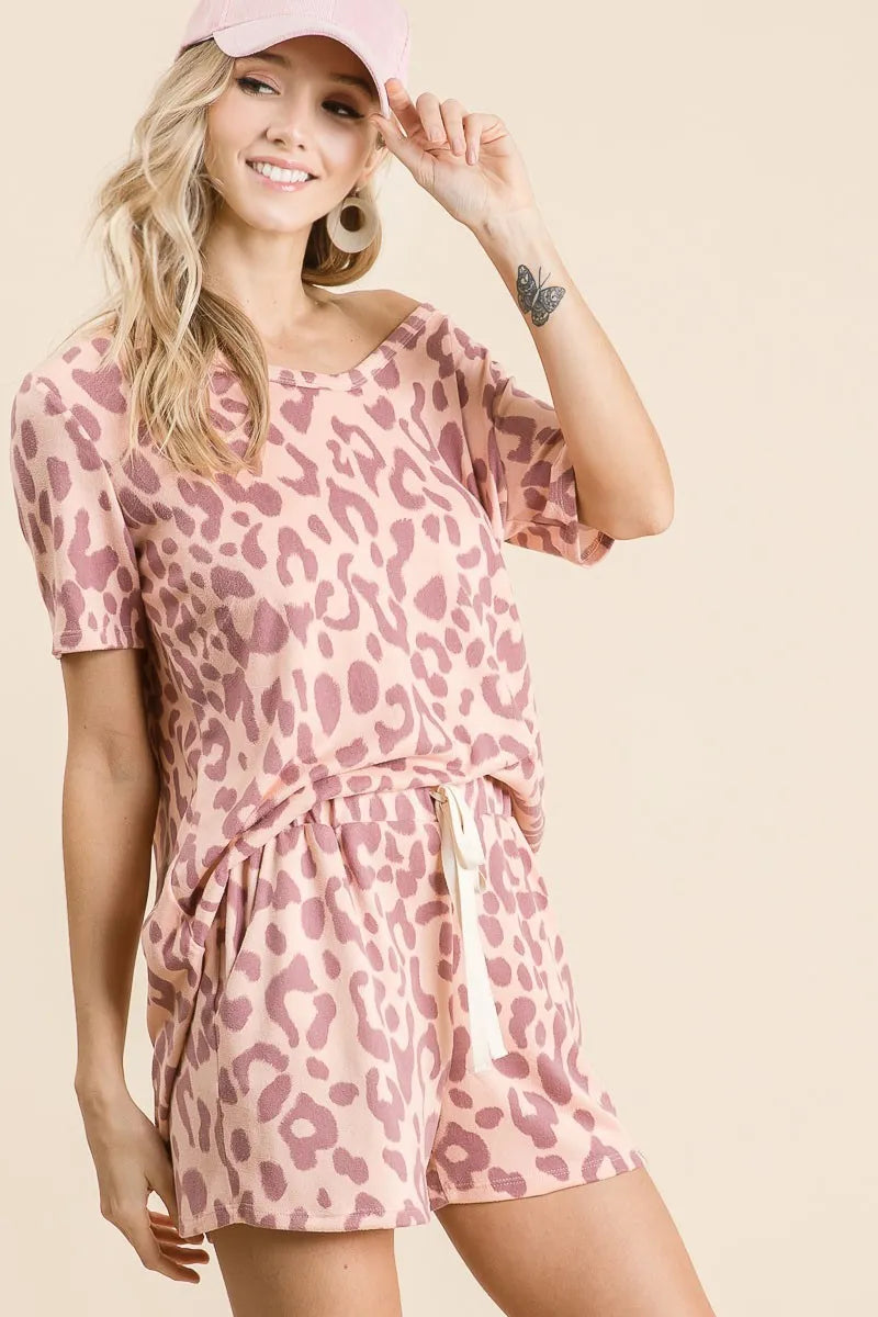 Woman wearing a pink leopard print dress and matching cap on a beige background