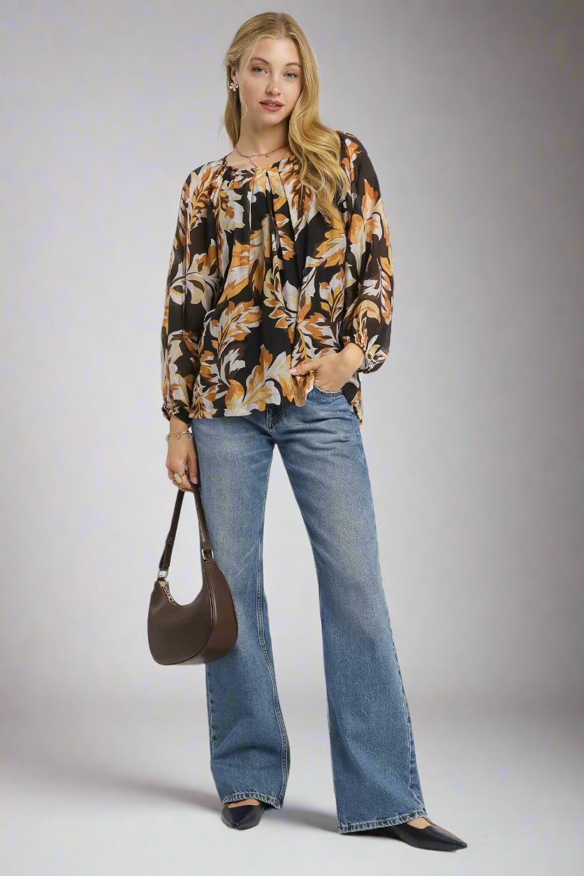 Woman wearing a patterned blouse and blue jeans with a brown handbag on a white background