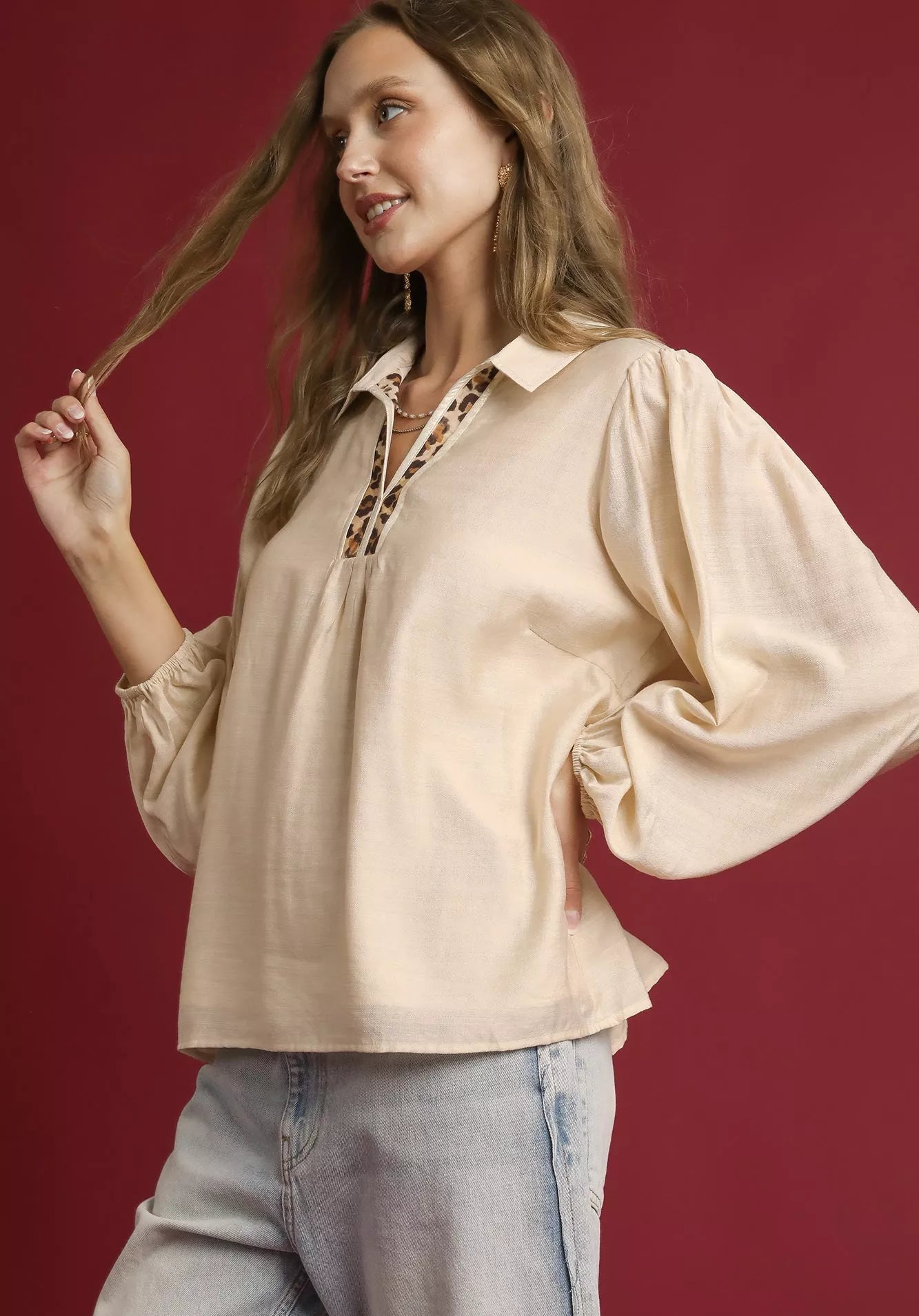 Woman wearing a beige blouse with a red background