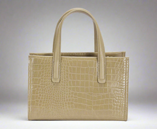 Beige handbag with crocodile texture on a white background
