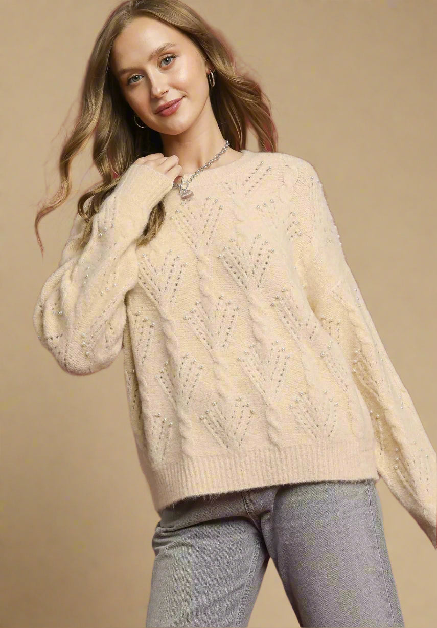 Woman wearing a cream sweater with a red background