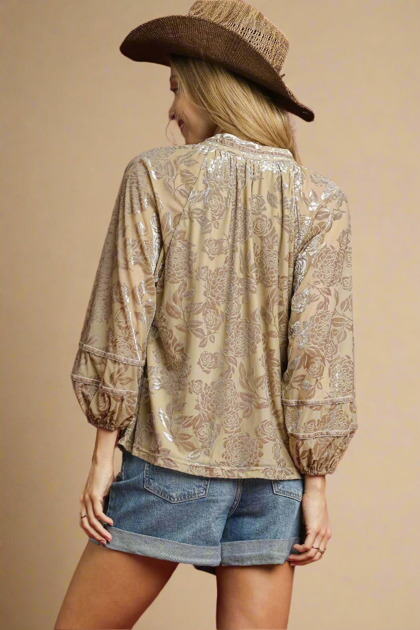 Person wearing a patterned blouse and denim shorts with a cowboy hat on a beige background