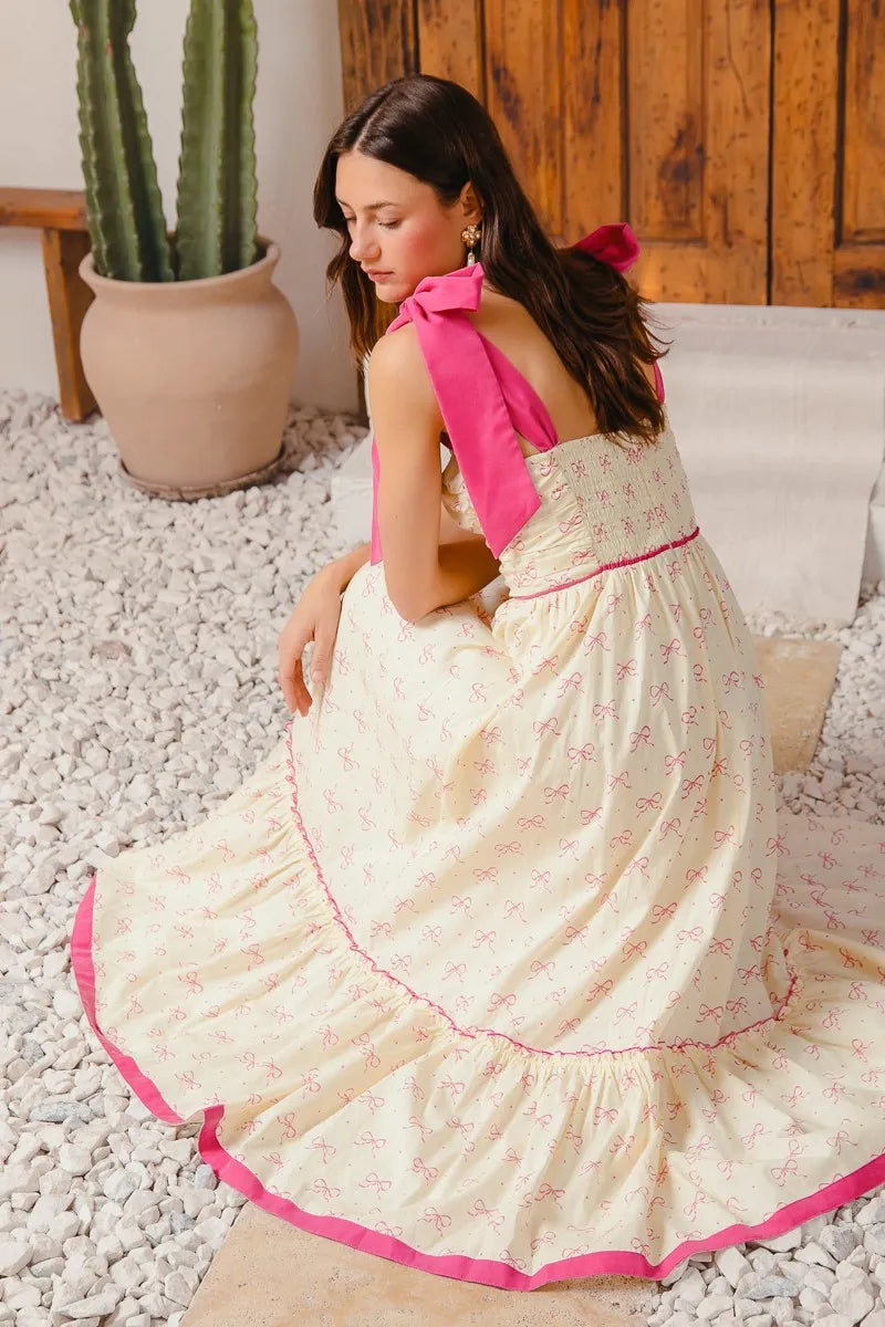 Woman in a white dress with pink accents sitting on a stone floor.