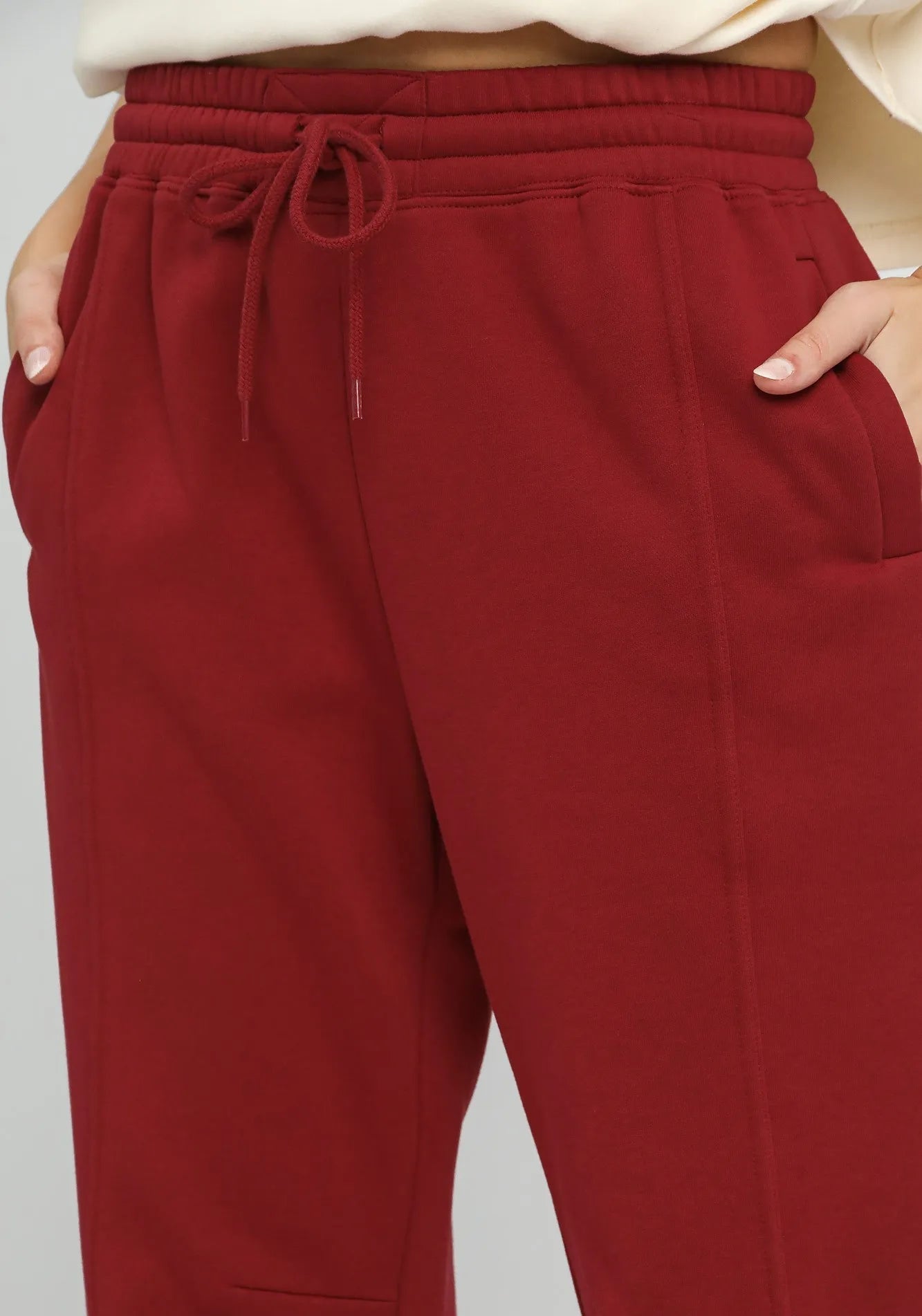 Burgundy pants with a drawstring waist on a light gray background