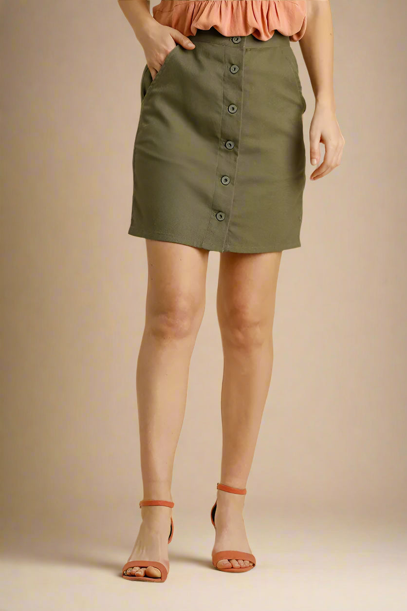 Person wearing an olive green skirt with a plain background