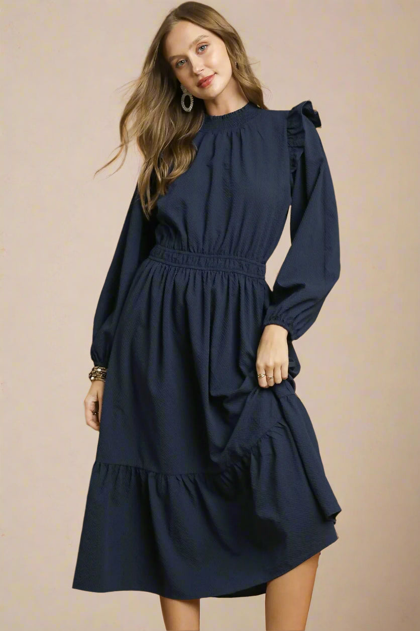 Woman wearing a navy dress against a beige background