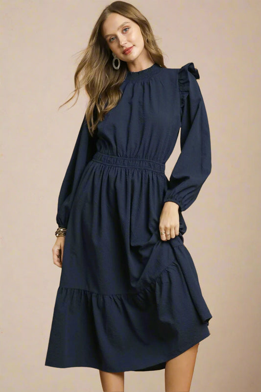 Woman wearing a navy dress against a beige background