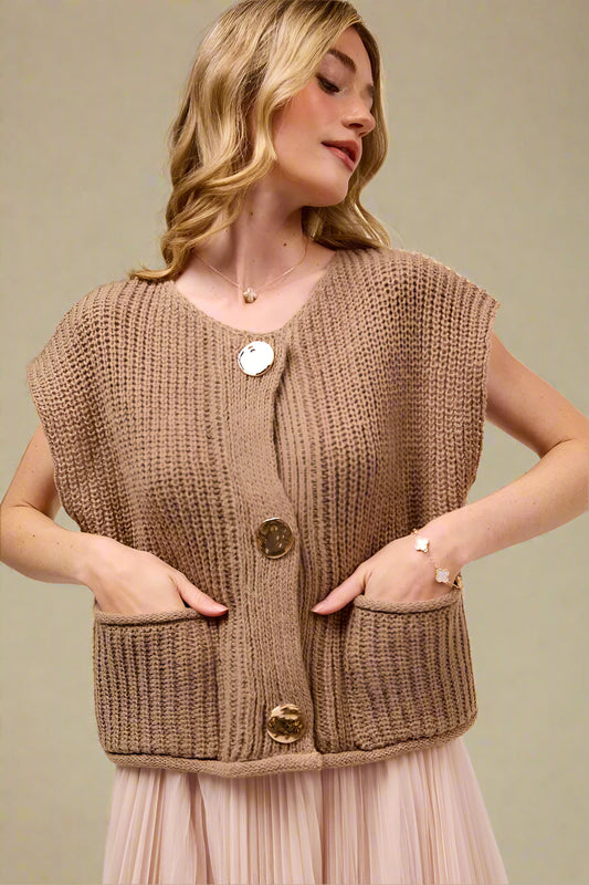 Woman wearing a brown knitted vest with gold buttons on a beige background