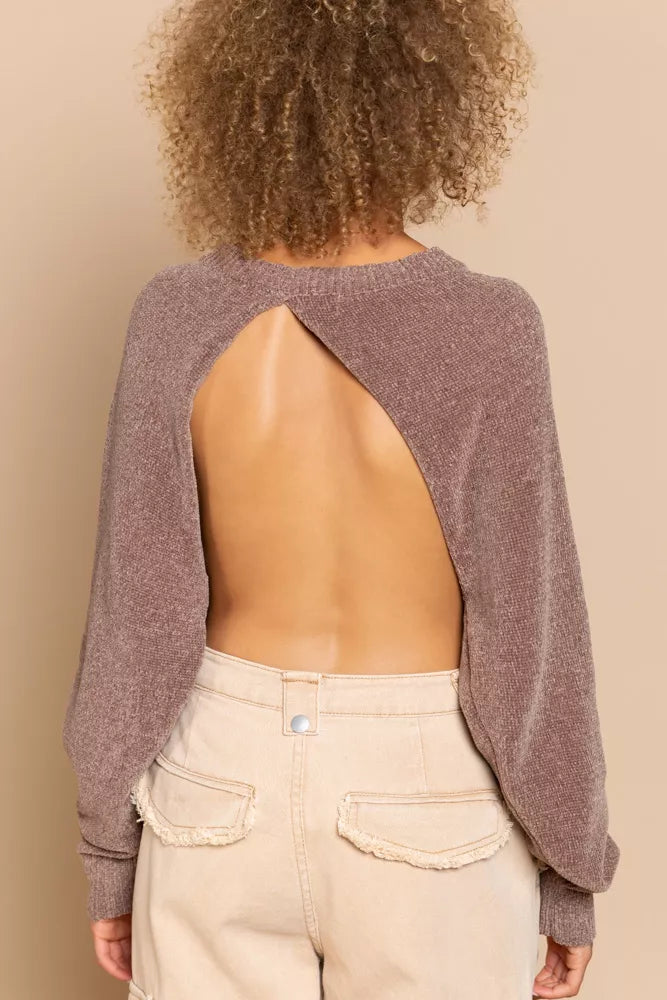 Person wearing a open-back sweater and beige pants on a beige background