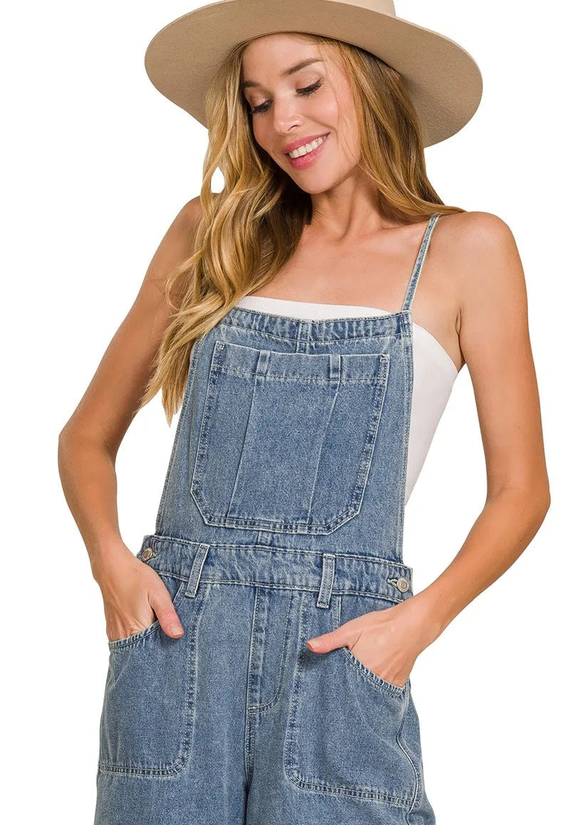 Woman wearing denim overalls and a beige hat on a white background