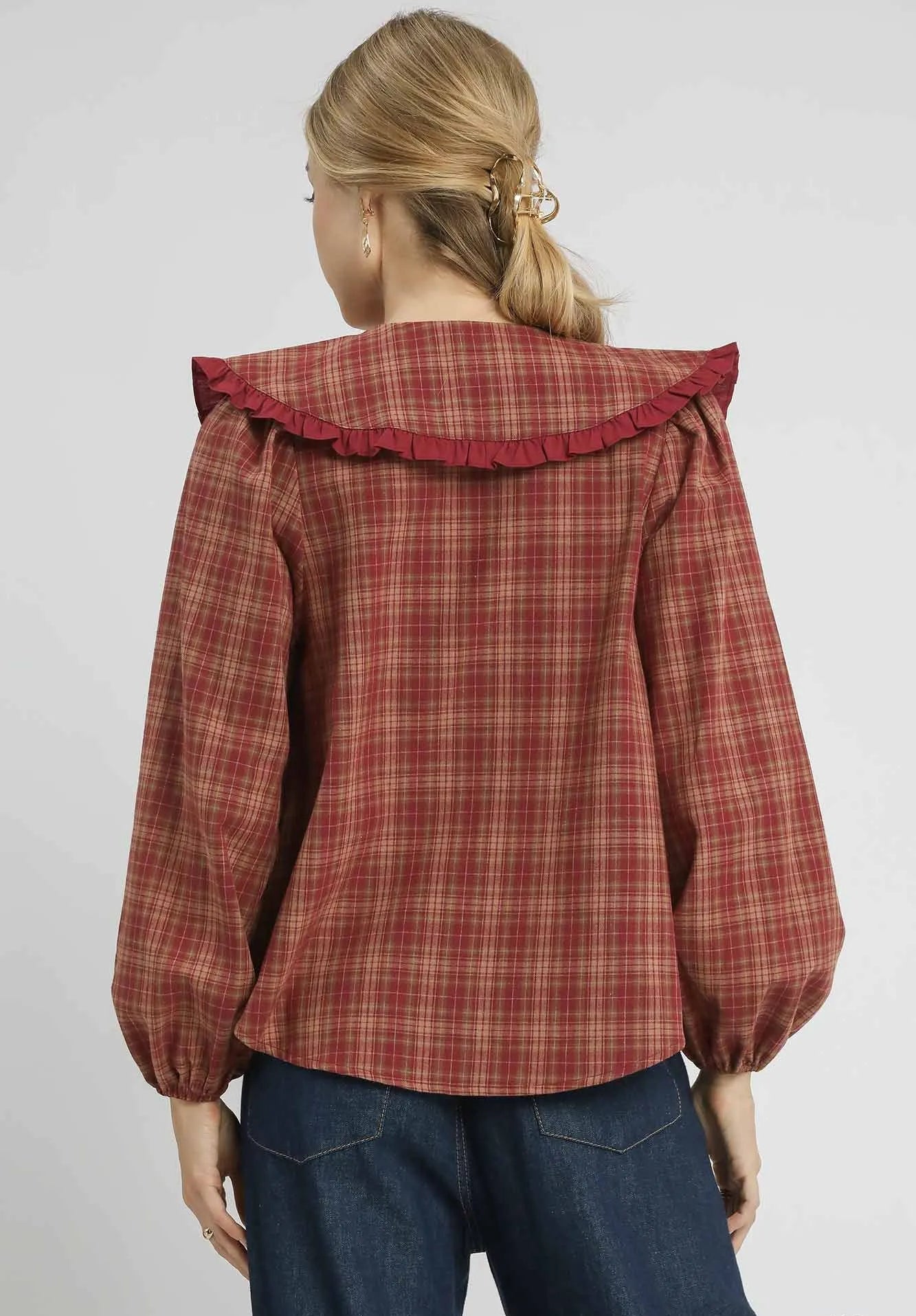 Person wearing a red plaid shirt with ruffled collar on a white background