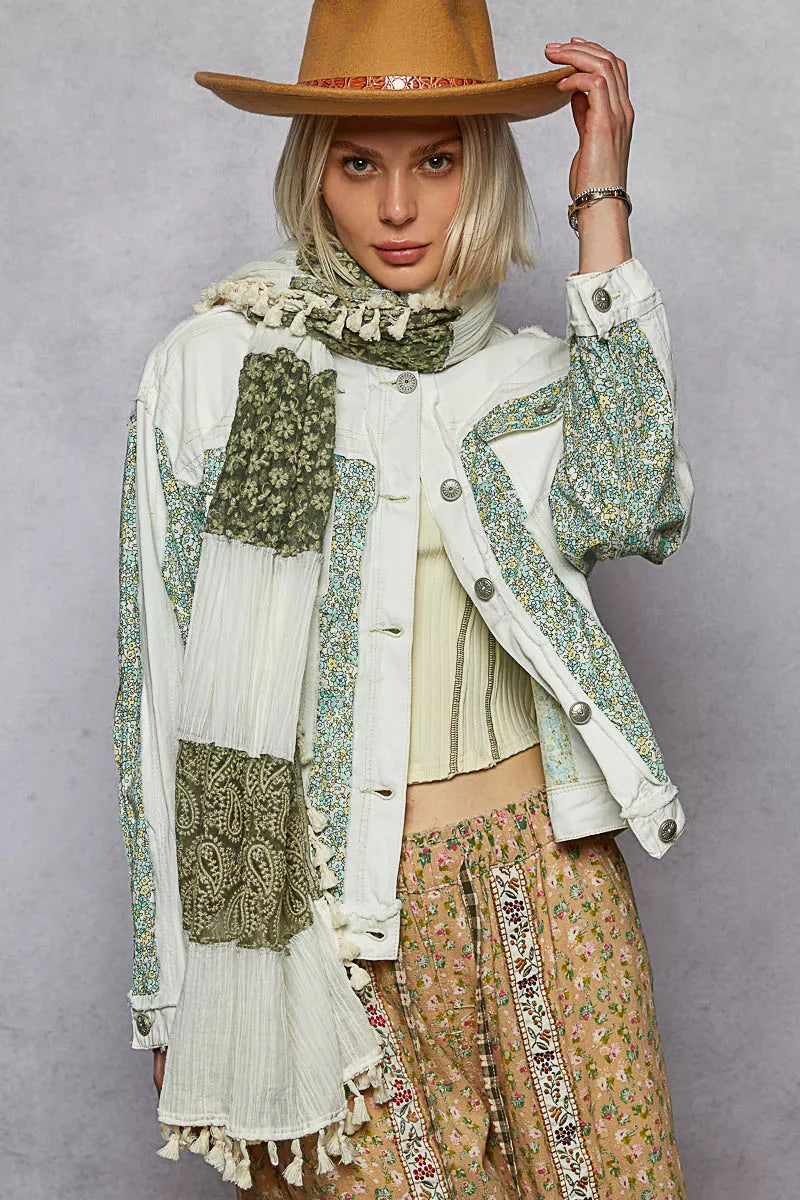 Woman wearing a patterned jacket, scarf, and hat against a gray background