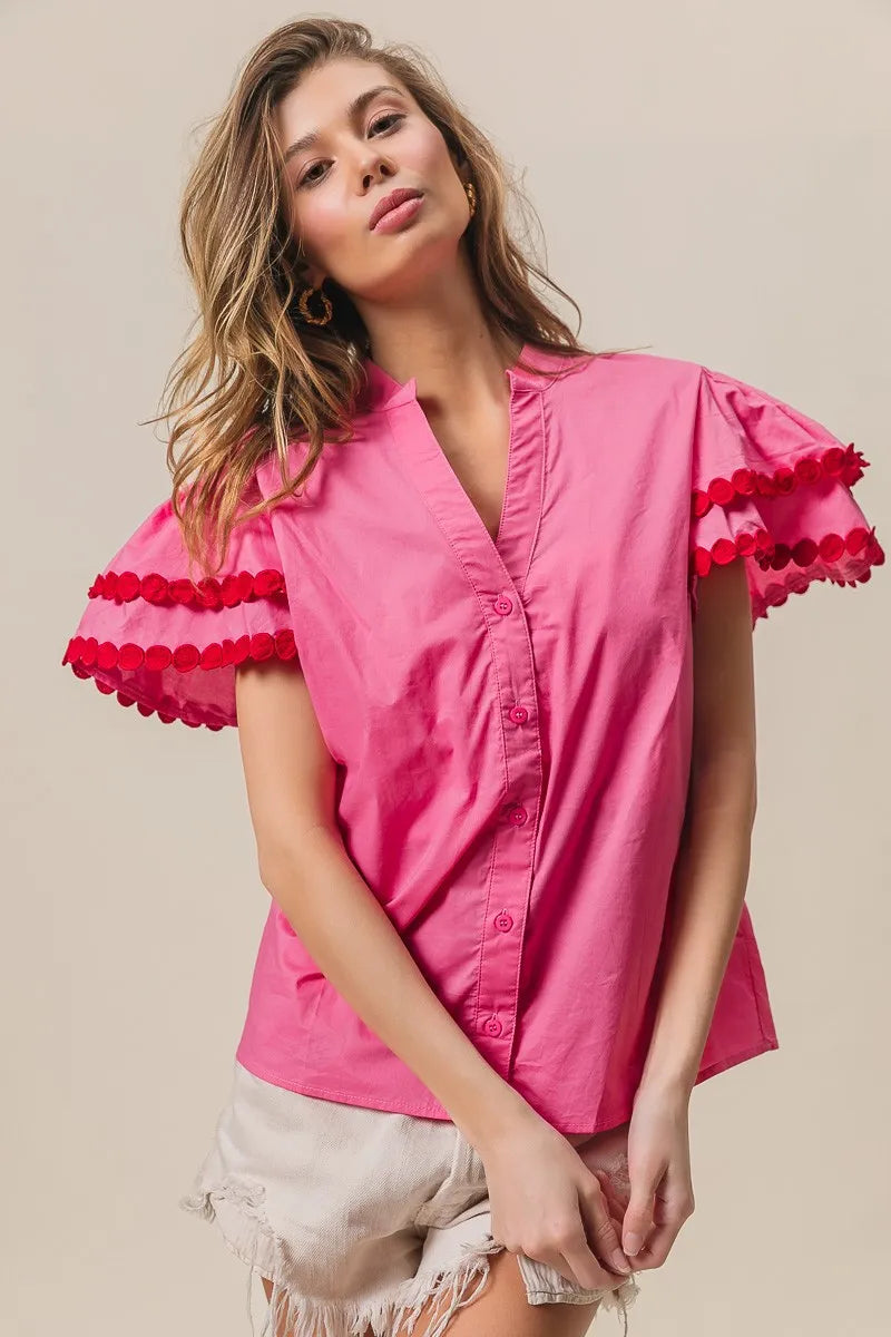 Woman wearing a pink blouse with red ruffled sleeves on a beige background