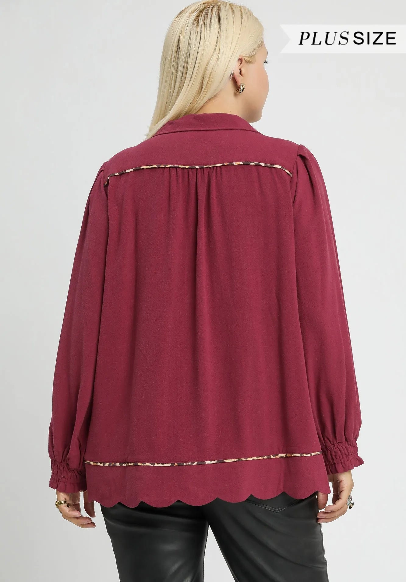 Maroon blouse with scalloped hem on a plain background