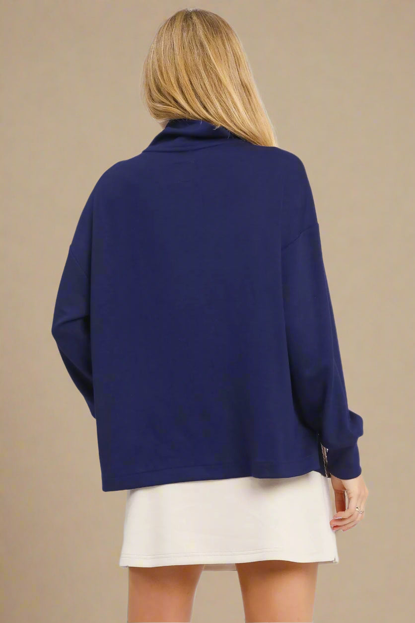 Person wearing a blue sweater and beige skirt on a white background