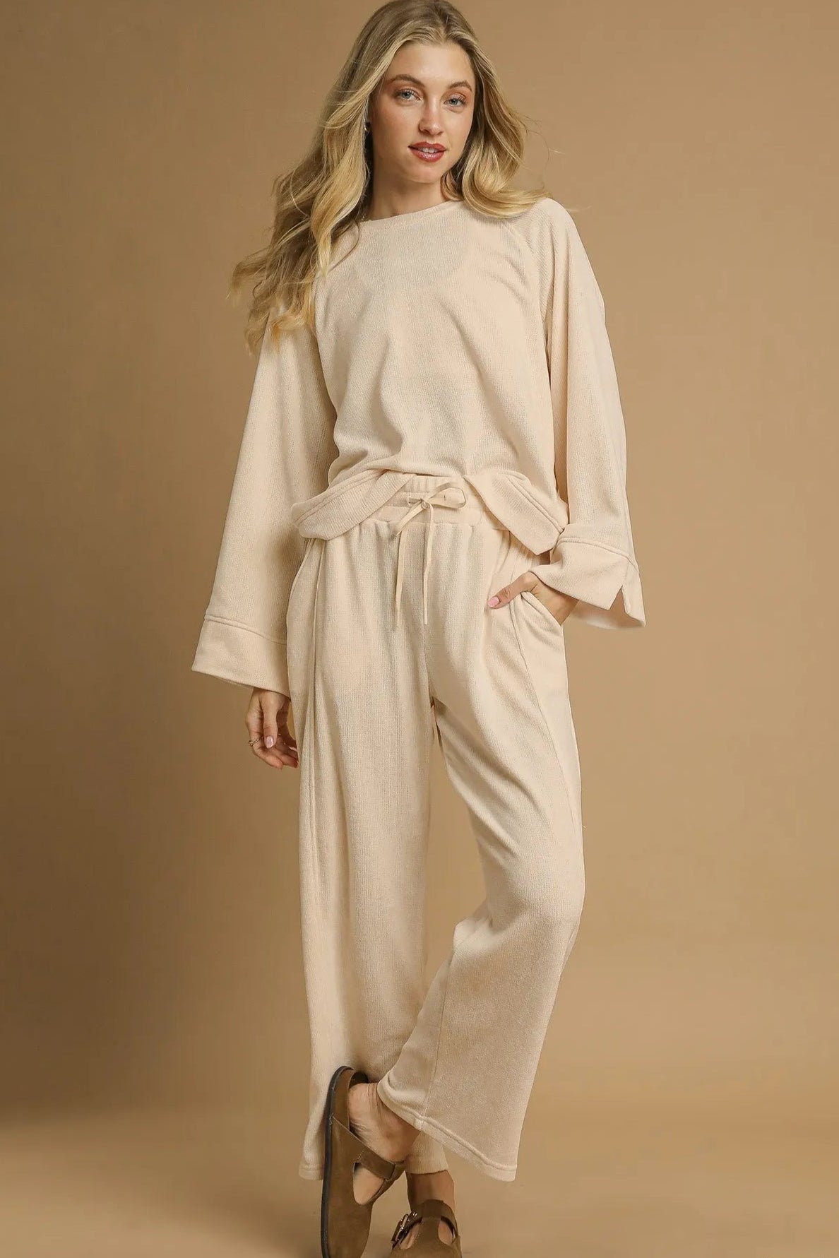 Woman wearing a cream-colored outfit on a beige background