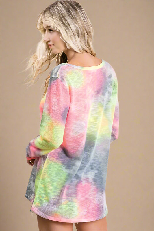 Woman wearing a colorful tie-dye shirt against a plain background
