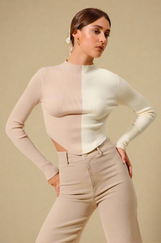 Woman wearing a color-blocked sweater and beige pants against a plain background
