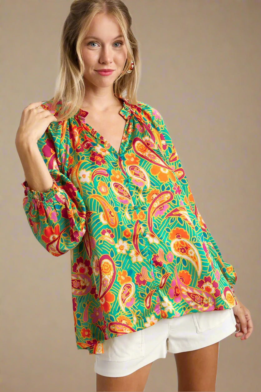 Woman wearing a colorful patterned blouse with a plain background