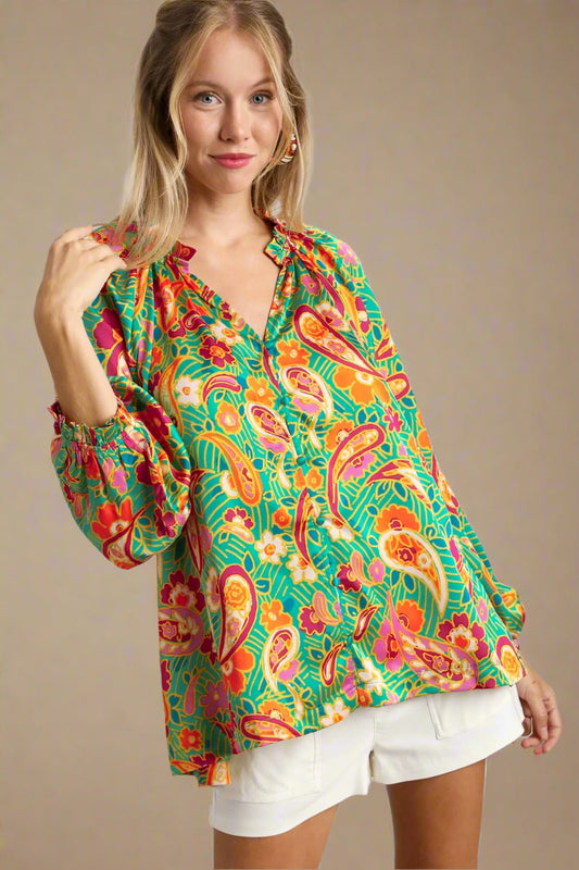 Woman wearing a colorful patterned blouse with a plain background