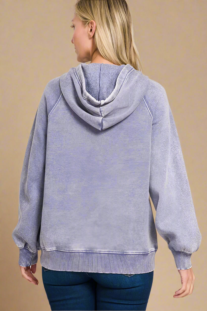 Person wearing a washed periwinkle hoodie on a beige background