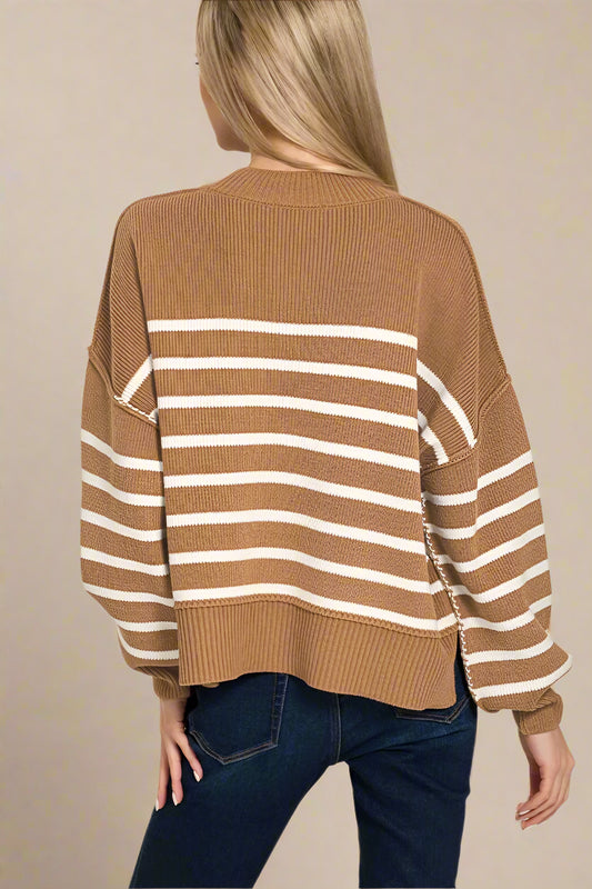Woman wearing a brown and white striped sweater with blue jeans on a beige background