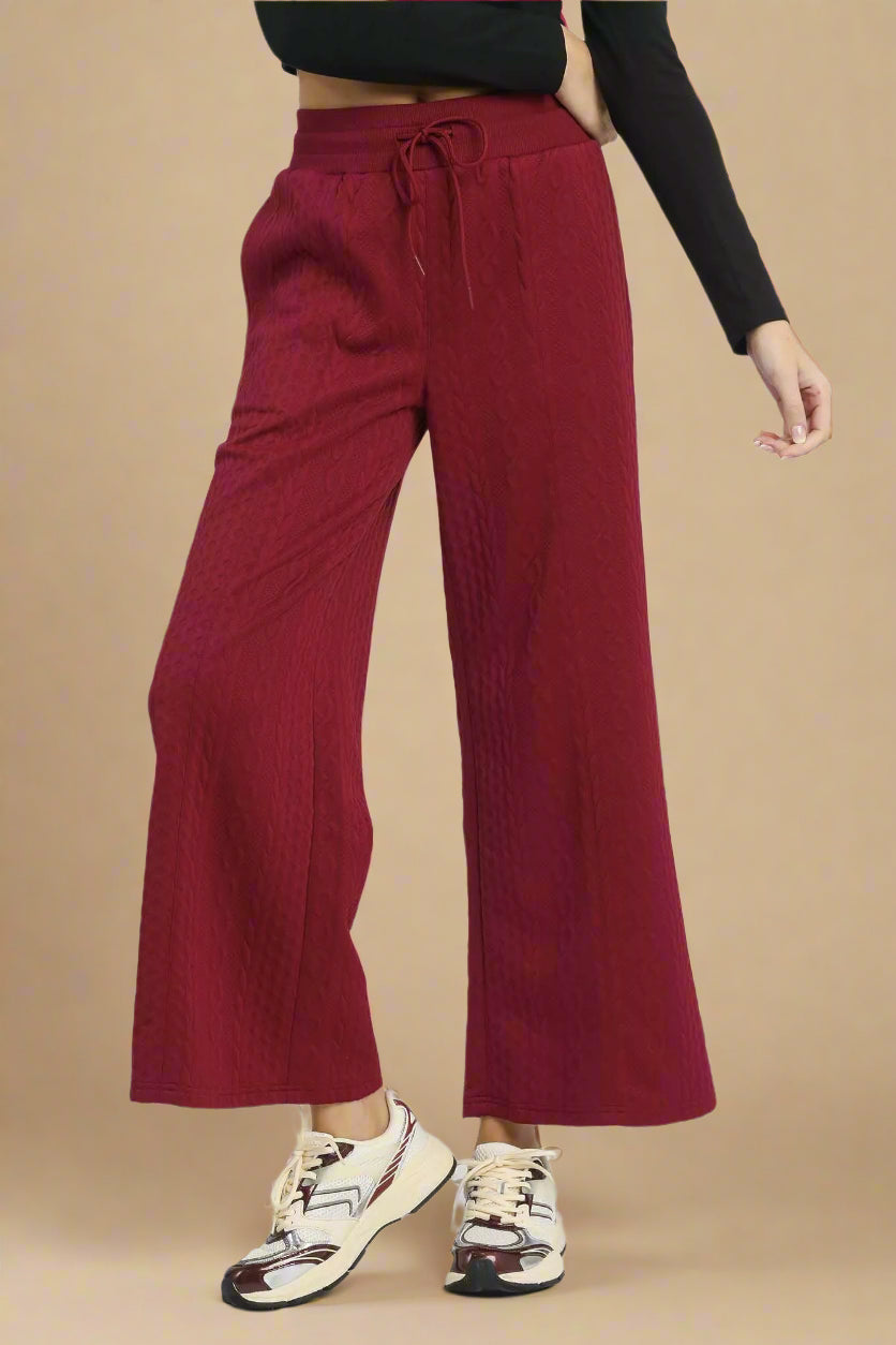 Burgundy wide-leg pants worn by a person on a white background