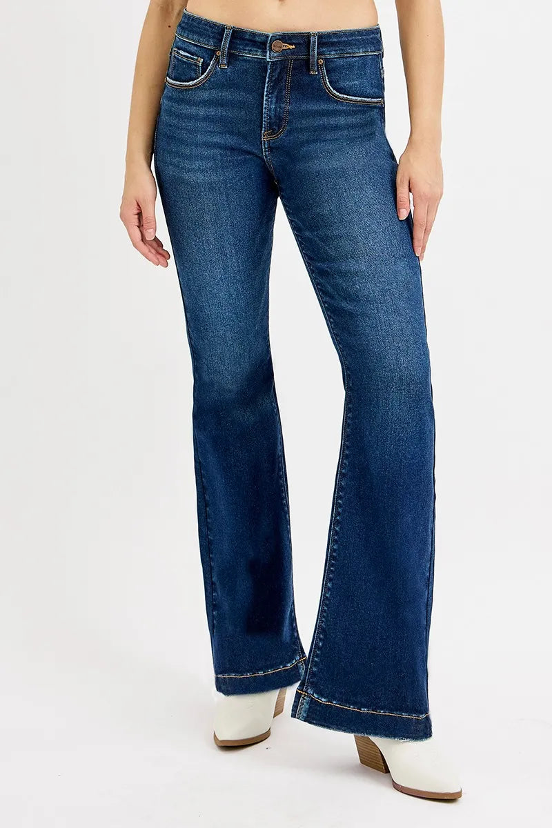 Blue flared jeans worn by a person on a white background